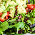 Nutritious low-calorie organic vegetable salad made from green leaves and tomato and avocado seasoned with olive oil will help the body get the necessary vitamins and normalize the stomach work